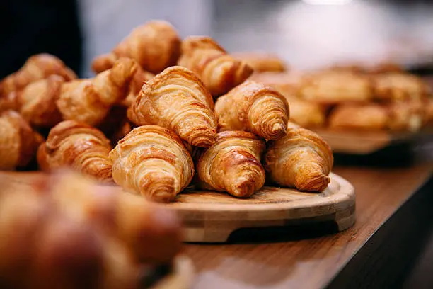 Een smaakvol assortiment van verschillende soorten Frans brood, waaronder baguettes, croissants, pain de campagne en brioche, gepresenteerd op een houten plank en klaar om te worden genoten bij een heerlijke maaltijd.