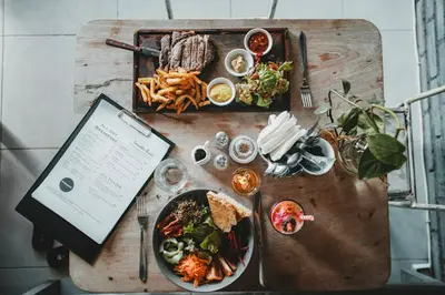 Een prachtig gedekte tafel vol met heerlijke Franse gerechten, waaronder coq au vin, bouillabaisse, camembert en tarte Tatin, omgeven door de sfeer van een authentiek Frans restaurant.